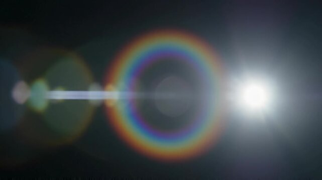 Elegant lens flare on black backdrop concept. Bright sun with colorful halo and lens flare effect in dark sky