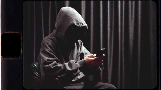 Anonymous hooded hacker using a smartphone