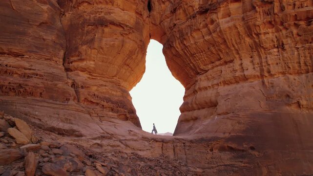 Discovering AlUla in Saudi Arabia, walking on the rock. Landscape with huge sandstone rocks of Arabic Peninsula, woman tourist climbing