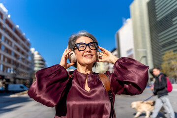 Mature woman enjoying music listening headphones city street © unai