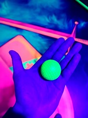 Hand holding glowing golf ball in blacklight mini golf © O-Trism Picture