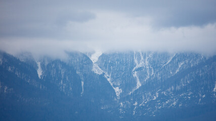 Fototapeta premium Snow-capped mountains partially hidden by clouds