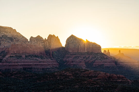 Sunrise starburst behind jagged rock formation