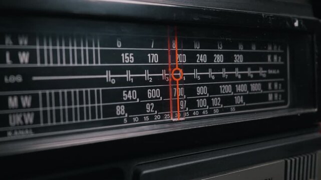 Vintage analog radio tuner displays frequency bands and a red indicator needle. Nostalgic concept of retro broadcasting technology and classic media.