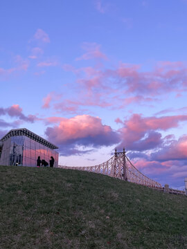 Queensboro Bridge and Cornell Tech building silhouette against dramatic pink purple sunset sky, Roosevelt Island, New York City, USA