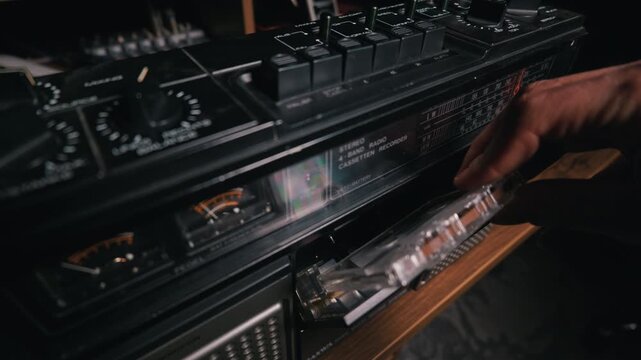 A person holds a clear audio cassette tape in front of a vintage analog stereo system. The nostalgic concept highlights retro music technology and an authentic throwback lifestyle.
