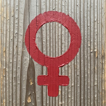 Red female gender symbol painted on wooden background  