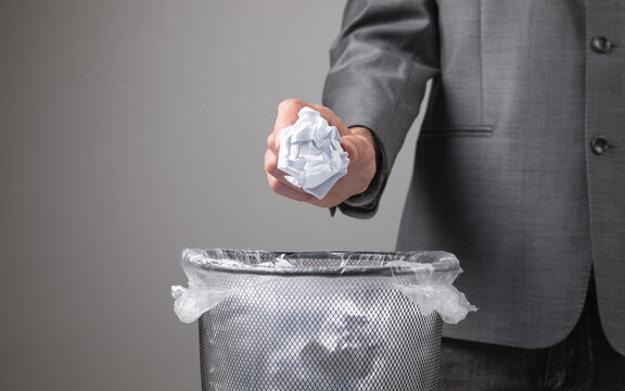 Man throwing crumpled paper into rubbish bin.