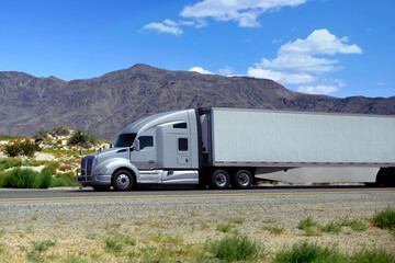 Obraz premium semi truck driving on highway through green nature and mountains. Commercial vehicle transport for logistics and freight shipping.