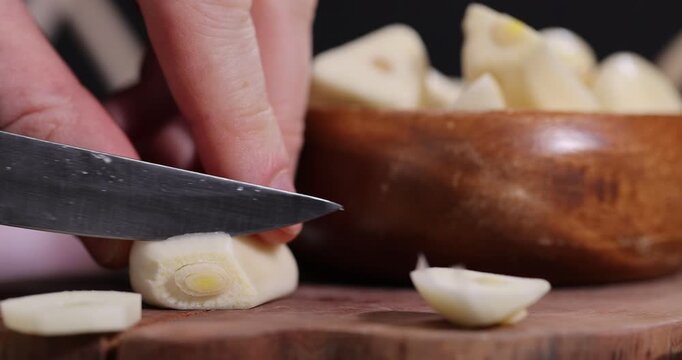 peeled and sliced purple garlic on the black kitchen table and peeled and sliced, fragrant fresh and natural garlic spices scattered on the kitchen table during cooking