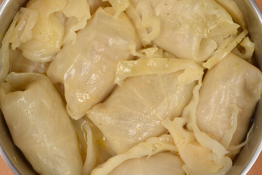 Cooked sarma (pickled cabbage leaf stuffed with meat and rice) is simmering in a metal pot with water and cabbage