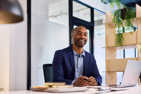 Smiling young black businessman working on laptop and smile
