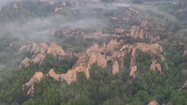 Aerial view of the unique Balze rock formations with mist and lush green forest in Reggello, Tuscany, Italy.