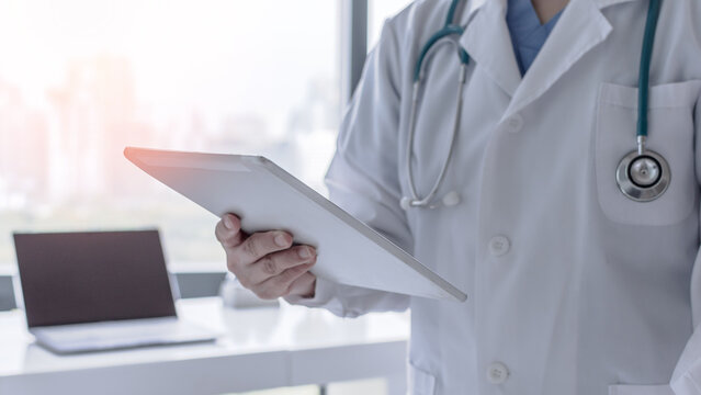 Telehealth and telemedicine by medical doctor or physician consulting patient&rsquo;s health online using mobile digital tablet in hospital for professional emergency tele-healthcare assistance service