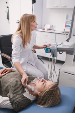 An endocrinologist examines a patient's thyroid gland using an ultrasound machine. Ultrasound machine