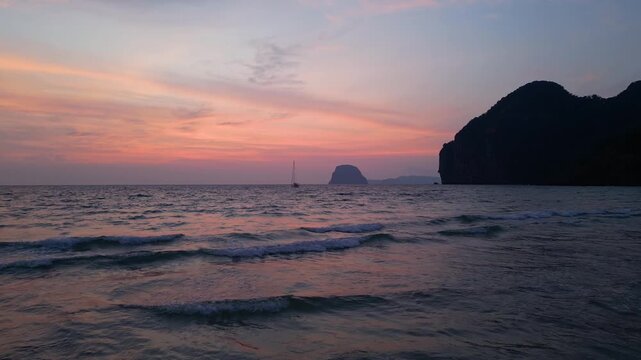 Koh Muk, Thailand: Cinematic backward footage of gentle waves breaking in Charlie beach in Koh Muk, South Thailand. Taken with smooth motion showing dramatic sunset