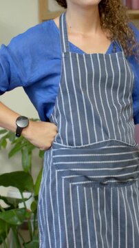 Vertical video: Camera tilting up, revealing aproned staff, hand tucking hair, showing plant care