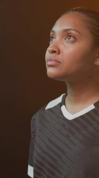 Woman athlete lifting chin gazing up while camera pulling back revealing soccer ball showing jersey