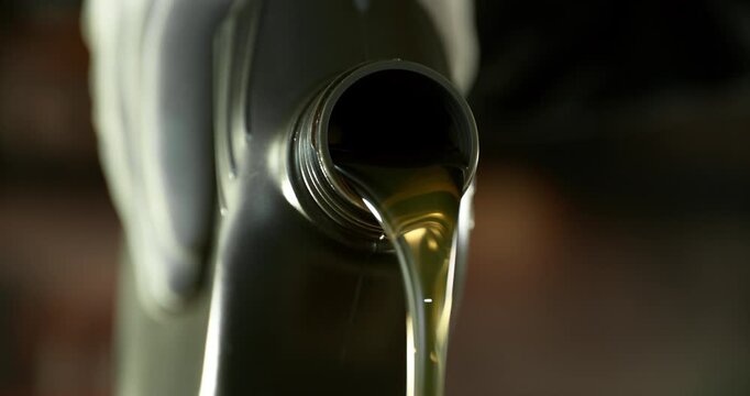 Super slow motion (1000 fps) cinematic shot of motor oil pouring from a container with dynamic camera movement around the bottle neck. Smooth golden liquid flow with bubbles and reflections.