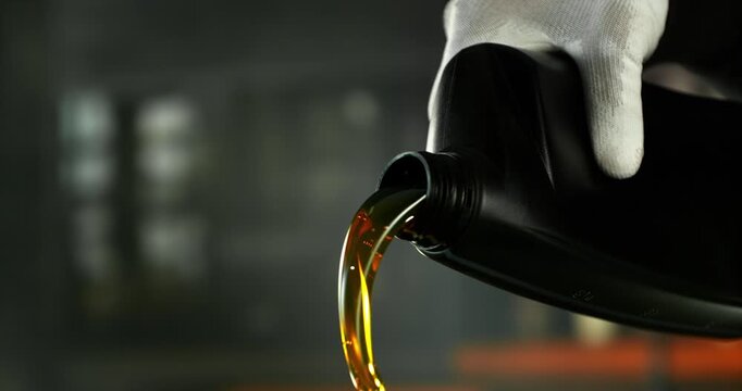 Super slow motion (1000 fps) cinematic shot of motor oil pouring from a container with dynamic camera movement around the bottle neck. Smooth golden liquid flow with bubbles and reflections.
