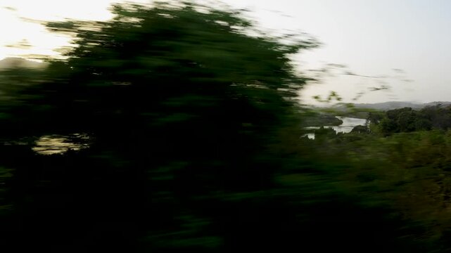 konkan railway peaceful countryside river scene with warm sunlight and greenery from train window