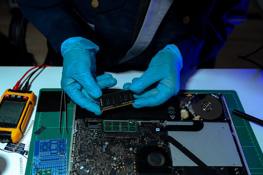 Computer Hardware Technician Repairing Motherboard with Soldering Iron in Electronics Lab.