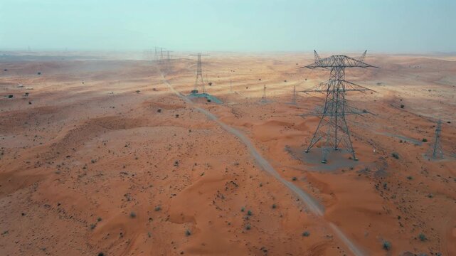 A high-angle drone view of High-voltage electric poles in the desert in UAE