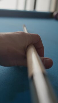 Vertical point of view closeup shot of player carefully aiming and striking cue ball during indoor pool game