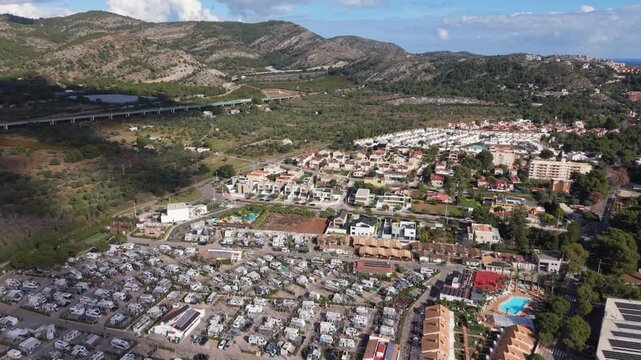 Benicassim,Castellon, Spain high slow forward drone footage towards the elevated A7 motorway, the Desert de les Palmes mountains over Bonterra Resort fields and housing on bright sunny day