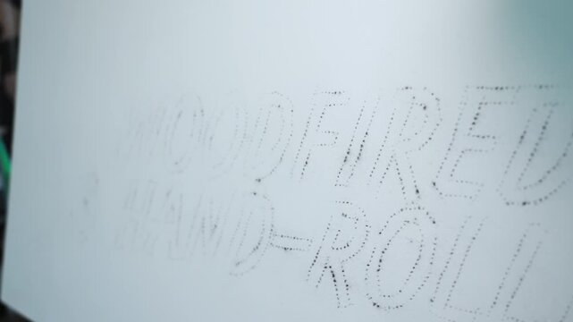 Close-up of charcoal dust pouncing technique used to transfer patterns onto a surface, showing traditional marking method, fine detail, and artistic preparation process.