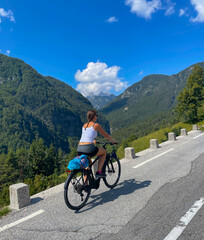 Fototapeta premium VERTICAL: Female traveler exploring the Soca valley and mountains on an ebike.