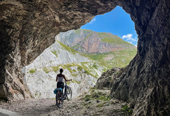 Fototapeta premium Young woman cycling in the Slovenian mountains stops at a scenic viewpoint.