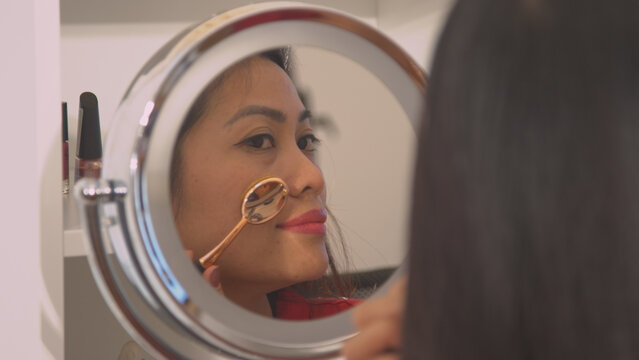 CLOSE UP: Mirror reflection of beautiful young woman applying contour make up