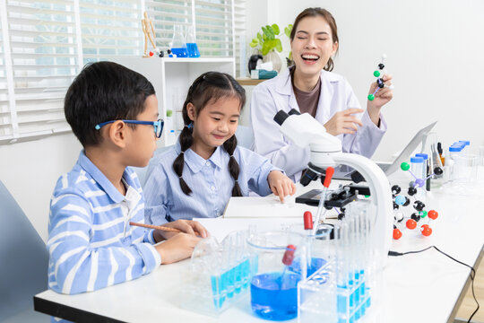 Teacher mentors students in classroom science experiment, combining chemistry learning with research activity, equipment use, and test tube observation to build skills, support, and curiosity