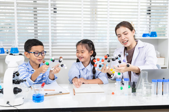 In chemistry classroom, elementary students perform science experiment using molecule models to build concentration, discovery, group skills, communication, and academic curiosity through fun activity