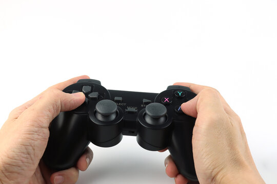 close up of hands holding black game controller joy stick isolated on white background concept of gaming, entertainment, and technology with focus on control buttons and analog sticks play station toy
