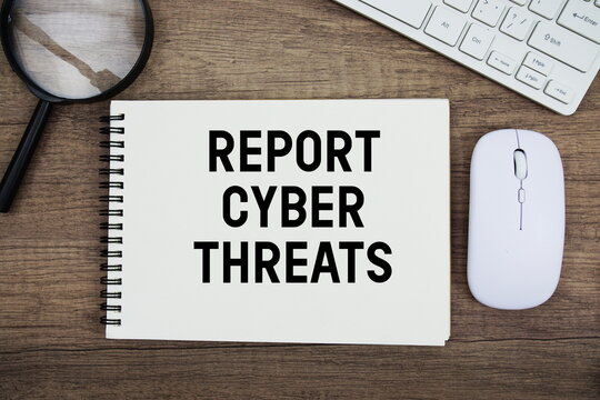 Report Cyber Threats text written on notepad with keyboard, optical mouse and magnifying glass on wooden background;