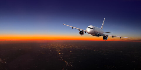 Airplane flying over city lights during sunset travel