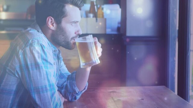 Man leaning reaching for cold pint, sipping pausing and gazing out window, bokeh highlighting pint