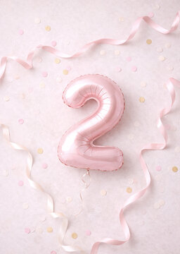 Pink number two balloon with confetti and ribbons on pastel background
