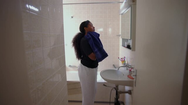 African American woman drying face with towel while standing in bathroom completing skincare routine and transitioning from cleansing to rest in calm home setting