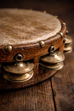 Close up of a vintage wooden tambourine with brass jingles on a wooden surface