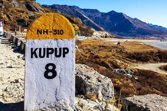 Milestone on NH-310 mountain road with Himalayan peaks in the background