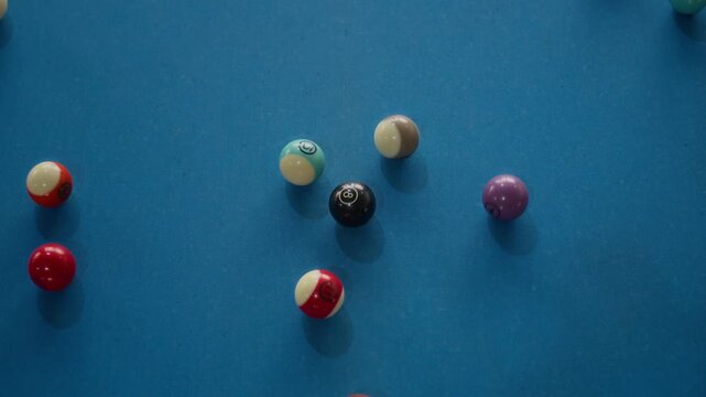 Close up shot of billiard balls scattering from triangle formation after powerful break shot on blue pool table