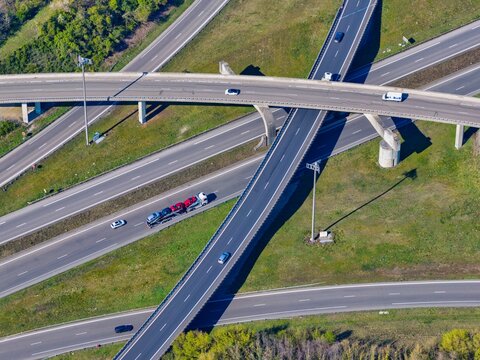 Aerial view of a multilane highway with multiple overpass intersections and sparse vehicles cutting through a green and brown landscape, Sausheim, Grand Est, France.