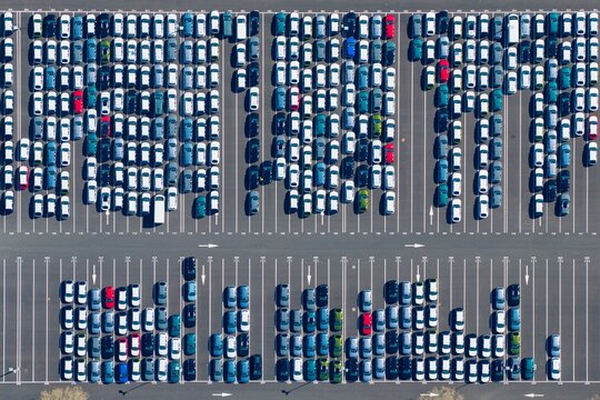 Aerial view of a vast car park filled with rows of vehicles in orderly lines, gleaming under the sun, a testament to organized urban space, Sausheim, Grand Est, France.