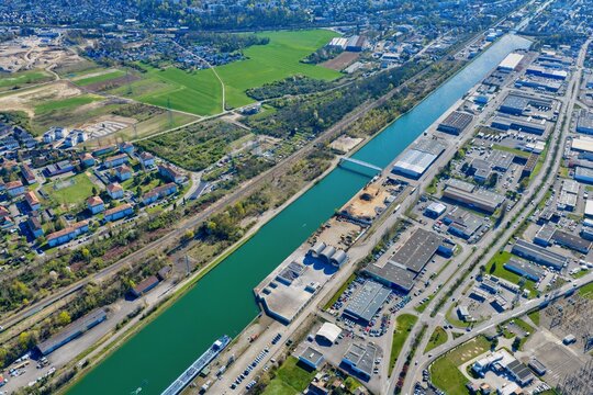Aerial view of the Canal du Rhone au Rhin cutting through the city, juxtaposing industrial zones with serene residential areas, Sausheim, Grand Est, France.