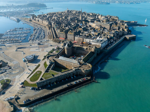 Aerial view of the walled city against the turquoise sea, a fortress with ramparts, and a harbor filled with boats, Saint-Malo, Brittany, France.