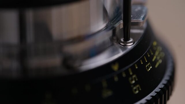 Extreme close-up of a Torx screw being carefully tightened into a PL bayonet mount on a cinema lens. Screw head and metal detail clearly visible. Precise and satisfying assembly footage.