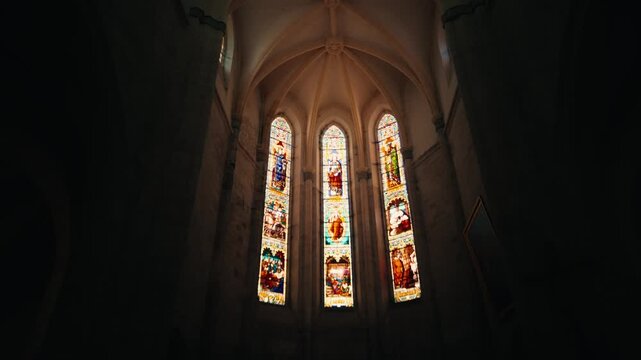 Detailed view of five colorful stained glass windows depicting religious figures in the church of Issigeac bastide. Interior shot.